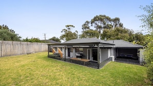 A residential property with a covered patio, a barbecue area, and a fenced backyard.