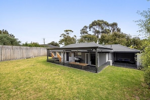 A residential property with a covered patio, a barbecue area, and a fenced backyard.