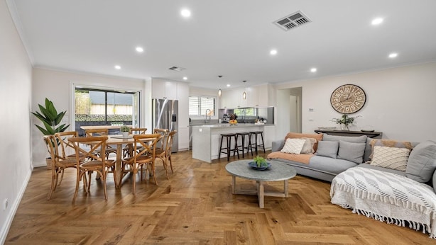 A modern living room with a dining area, kitchen, and a large window.