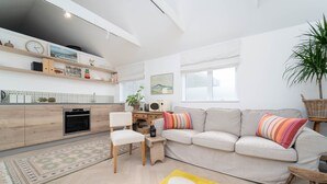 Een moderne woonkamer met een bank, stoelen, een salontafel en een geel vloerkleed.