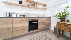 Een moderne keuken met houten kastjes, een inbouwoven en een raam met uitzicht.