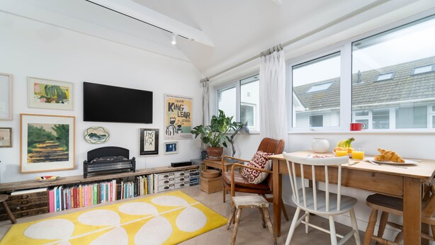 Een moderne keuken met een eettafel, stoelen en een groot raam.