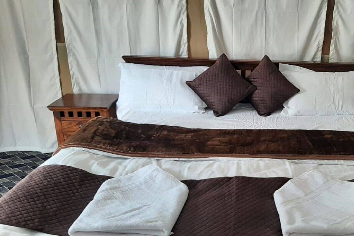 A neatly made bed with a brown quilt, white pillows, and a wooden headboard.