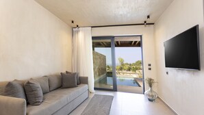 Una sala de estar moderna con un sofá, una mesa de centro, un televisor de pantalla plana y vistas a una piscina.