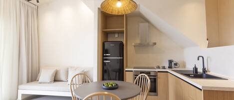 Una cocina moderna con comedor, que incluye una mesa redonda con sillas, un refrigerador negro y un armario de madera.