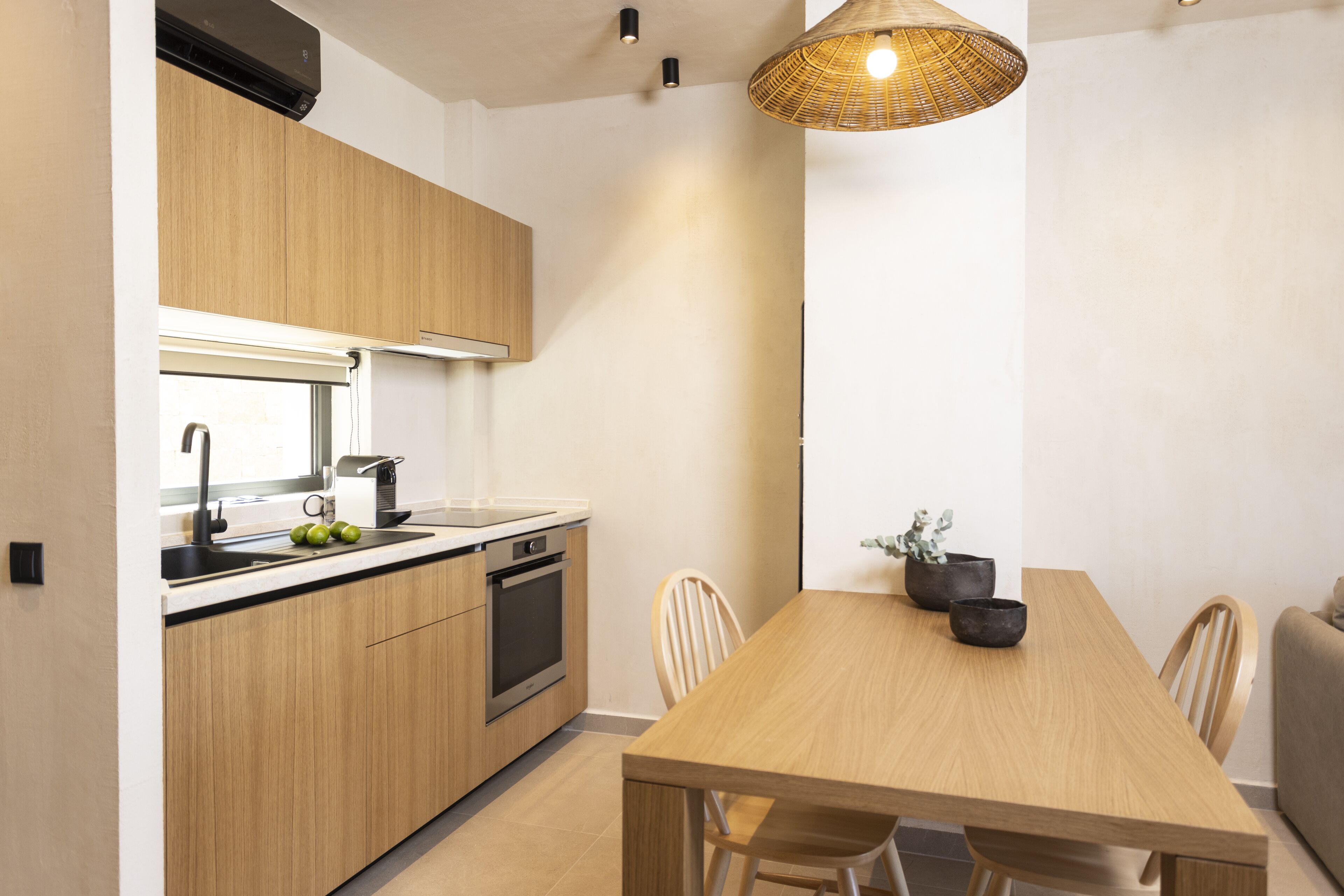 A modern kitchen with wooden cabinets, a built-in oven, and a dining area with a wooden table and chairs.