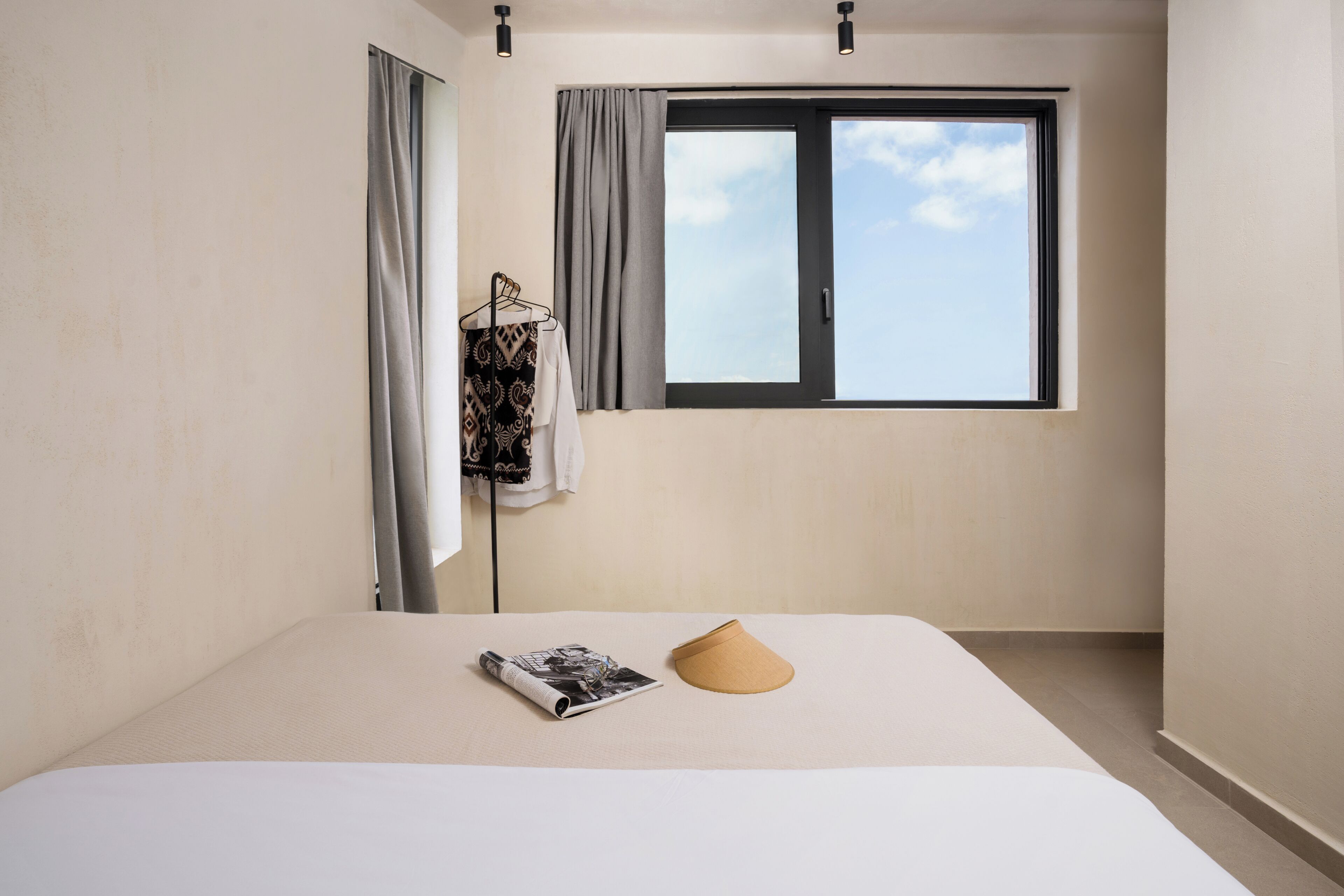 A bedroom with a bed, a window, and a hanging garment.