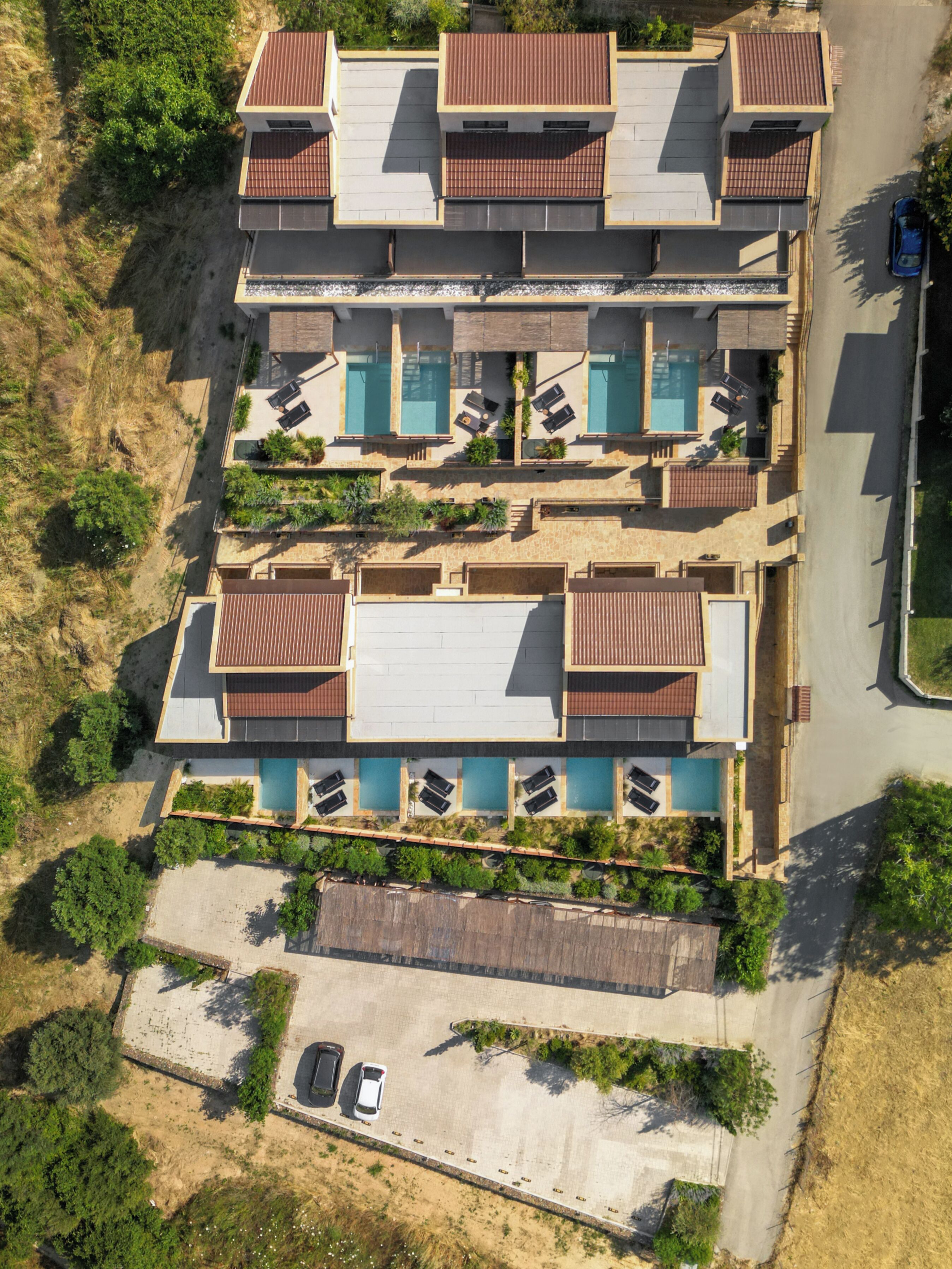 A multi-story building with a rooftop pool, a parking area, and a small garden.
