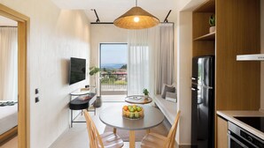 Una cocina moderna con un refrigerador negro, un comedor con una mesa redonda y sillas, y vistas al exterior a través de un amplio ventanal.