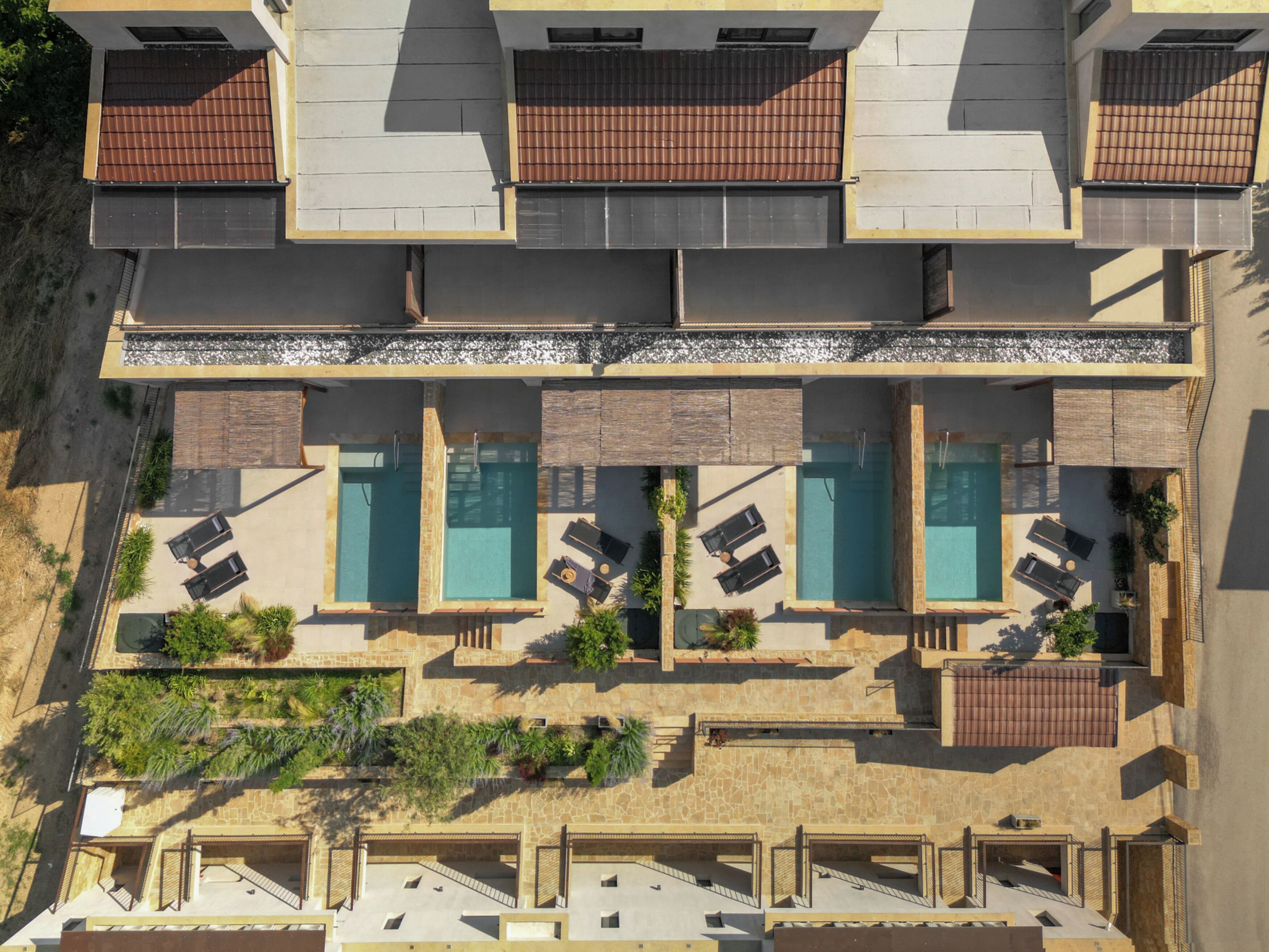 Et hotel med flere etager og en tagterrasse med swimmingpools og liggestole.