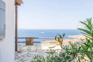 Un patio de piedra con vistas al mar y un barco a lo lejos.