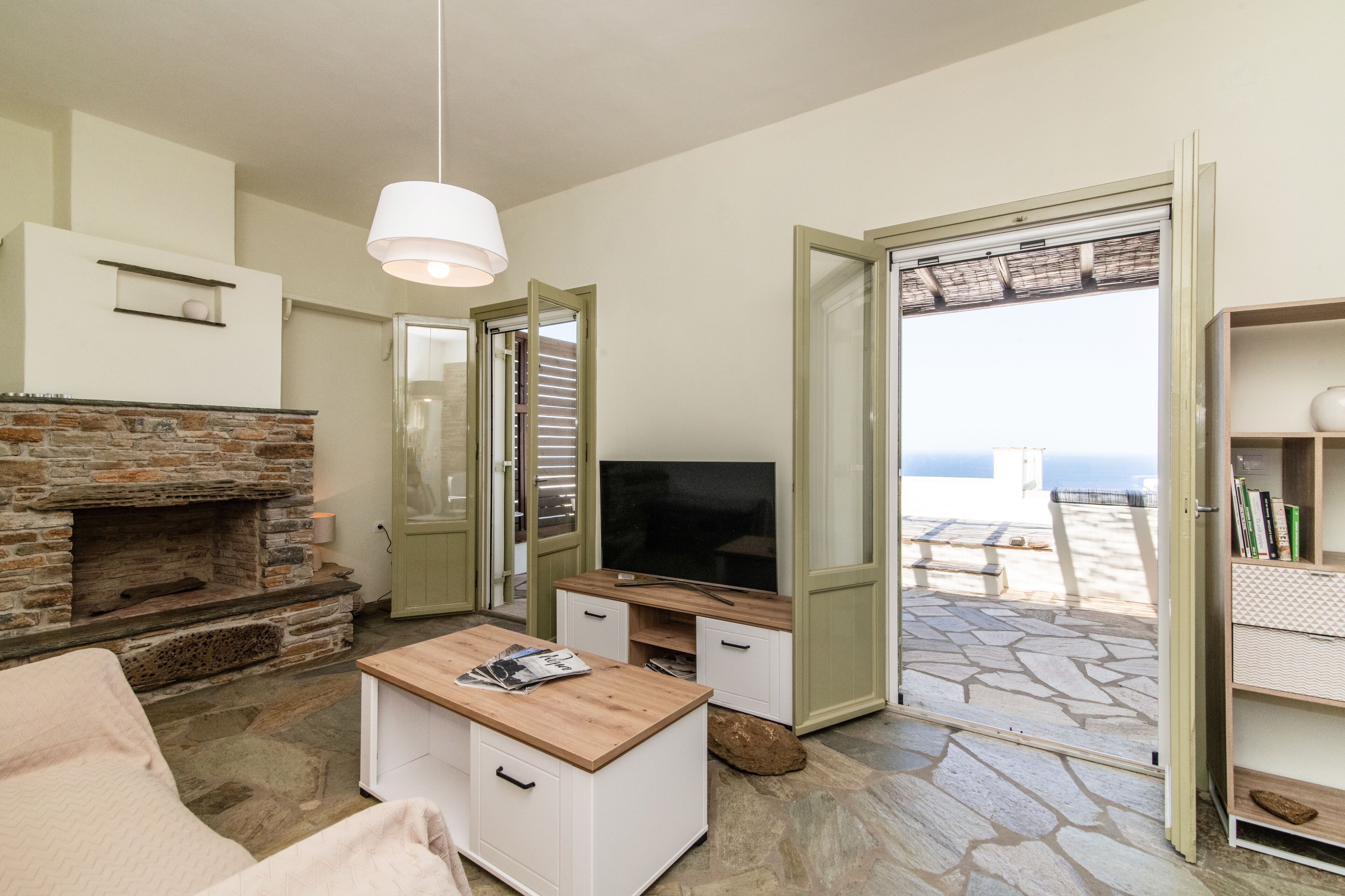A cozy living room with a stone fireplace, a television, and a wooden coffee table.