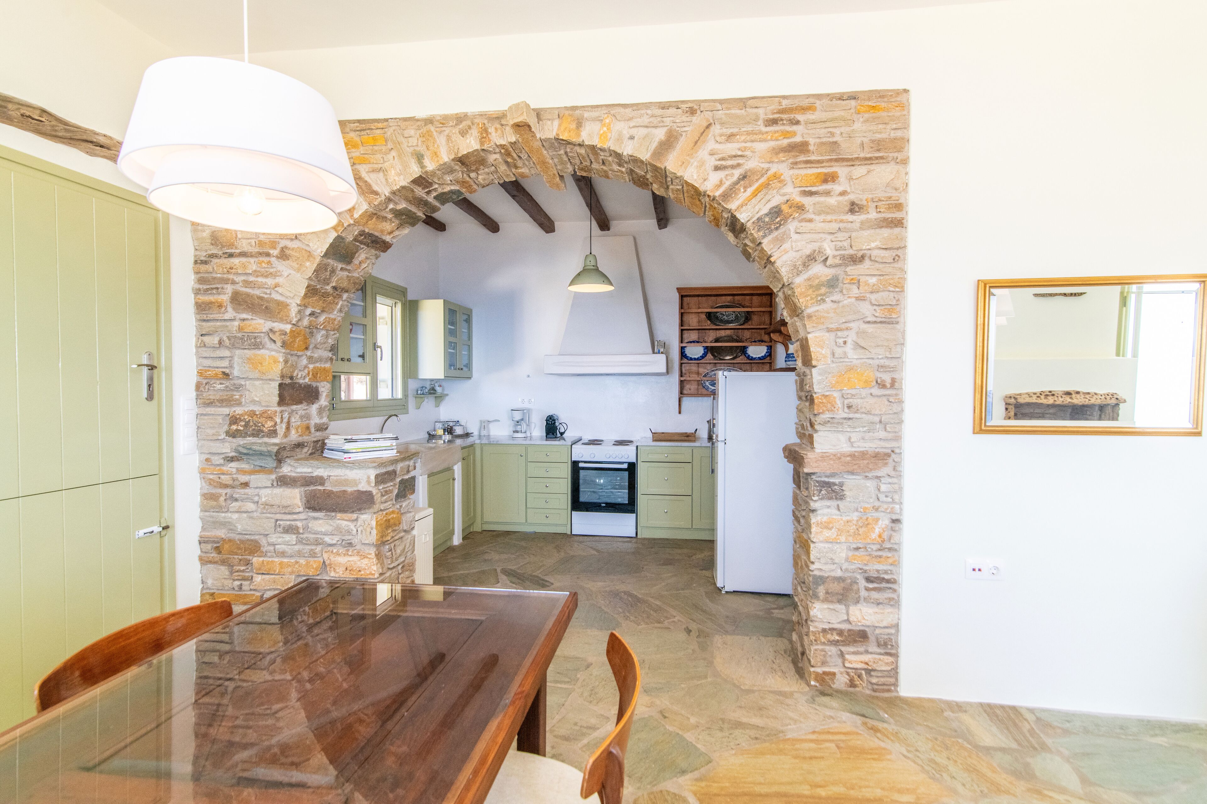 Una cocina con paredes de piedra, una mesa de comedor de madera y una lámpara colgante.