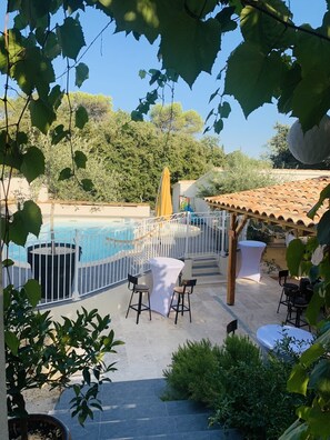 An outdoor pool area with a white fence, a yellow umbrella, and outdoor seating.