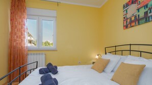 Une chambre d’hôtel avec un lit, des serviettes, une fenêtre, un radiateur et un tableau au mur.