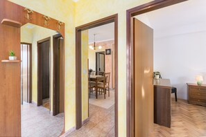 A spacious hallway with wooden doors and a dining area in the background.