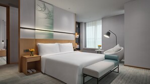 A modern hotel room with a large bed, bedside table, lamp, and a view of the city. - Q-Box Hotel Shangqiu Expo Center (Shangqiu)