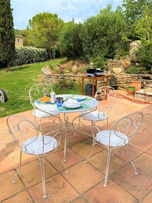 An outdoor patio with a round table and four chairs, surrounded by a stone wall and greenery. - Charming house with garden and swimming pool, close to the center. (Lorgues)