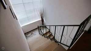A staircase with a metal railing, wooden steps, and a window with blinds. - Italianway - Piazza Nuova 3 (Centro Valle Intelvi)
