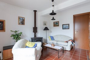 A living room with a sofa, a chair, a table, a lamp, a fireplace, and a door.
