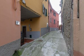 A narrow street with buildings on either side, a visible door, and a small sign on the wall.