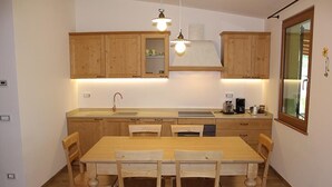 A compact kitchen with wooden cabinets, a central island, and pendant lighting. - Two Bedroom Apartment (IDRO)