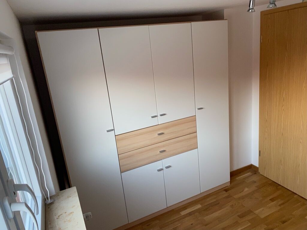 Una habitación con un armario grande, suelo de madera y una puerta.