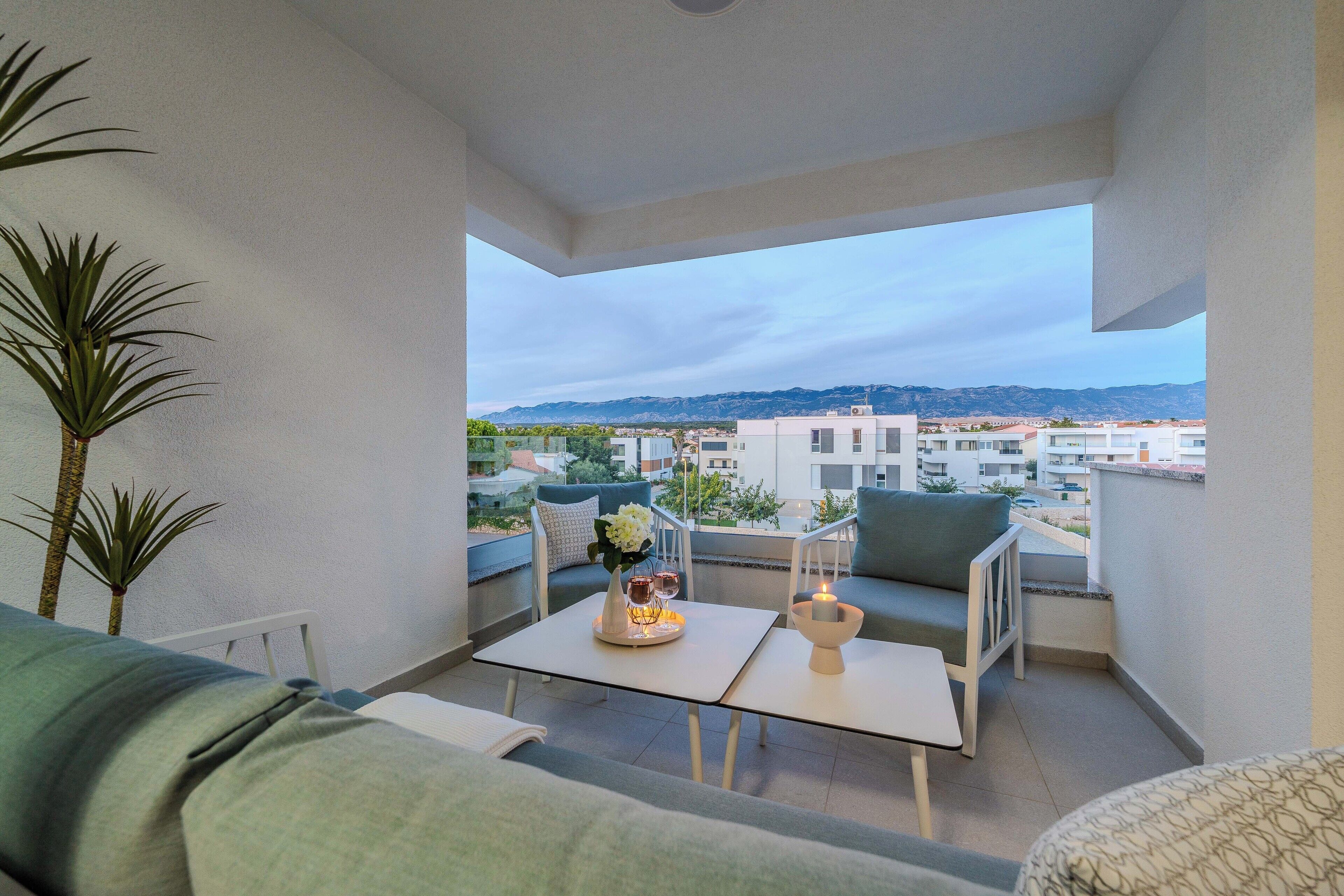 A balcony with a sofa, a small table, and a potted plant.