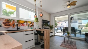 Una cucina moderna con isola in legno, zona pranzo con una sedia nera e ventilatore a soffitto.
