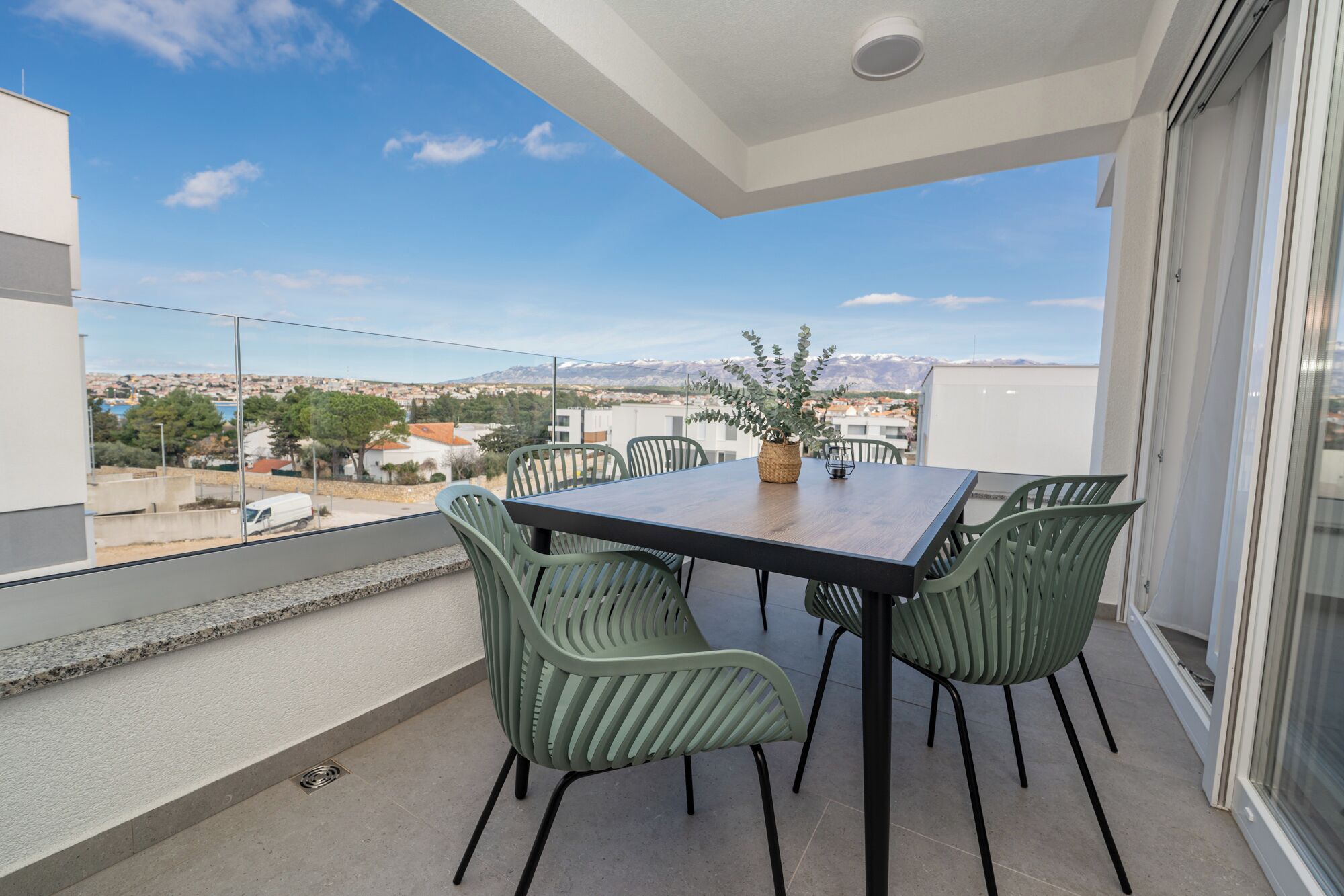 Un balcon avec une table et des chaises, un pot de fleurs et une vue sur le paysage urbain.