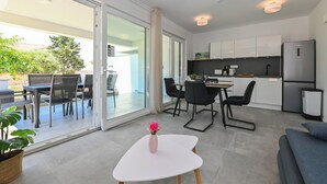 Una cucina moderna con mobili bianchi, un frigorifero e una zona pranzo con tavolo e sedie.