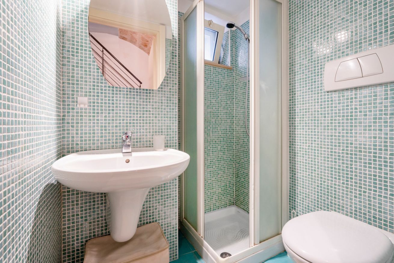 Un bany amb un lavabo blanc, un vàter i una cabina de dutxa de vidre.