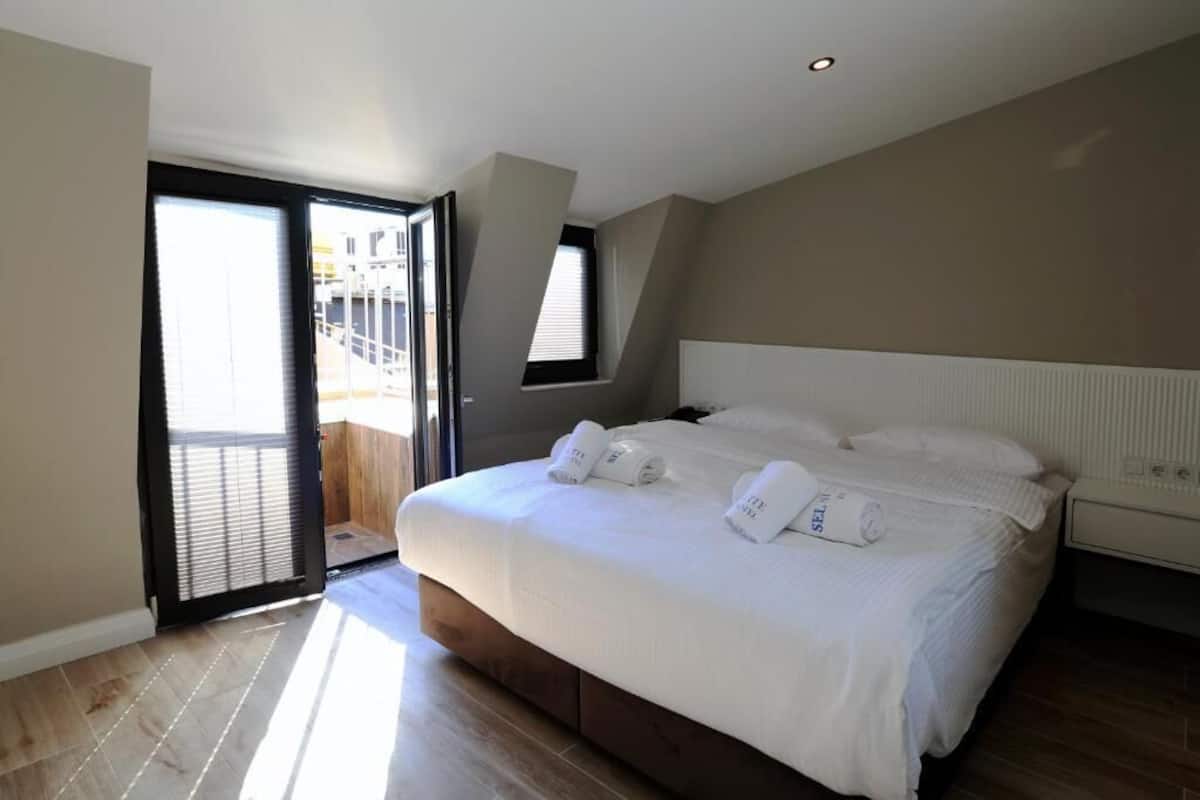 Un dormitorio con una cama grande, una ventana y una puerta que da a un balcón.