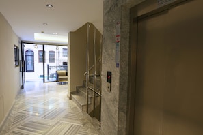 Experience the sleek, contemporary lobby with a polished floor, staircase, and elevator.