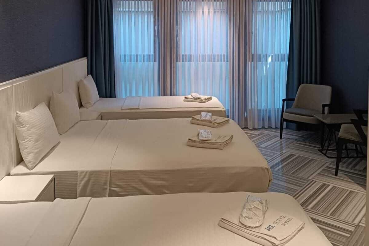 Habitación de hotel con dos camas, un sofá, una silla y una pequeña mesa.