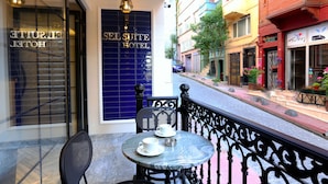 A hotel exterior with a blue entrance, a table with two chairs, and a decorative railing.