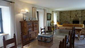 Una sala de estar con chimenea de piedra, muebles de madera y un cuadro grande en la pared.