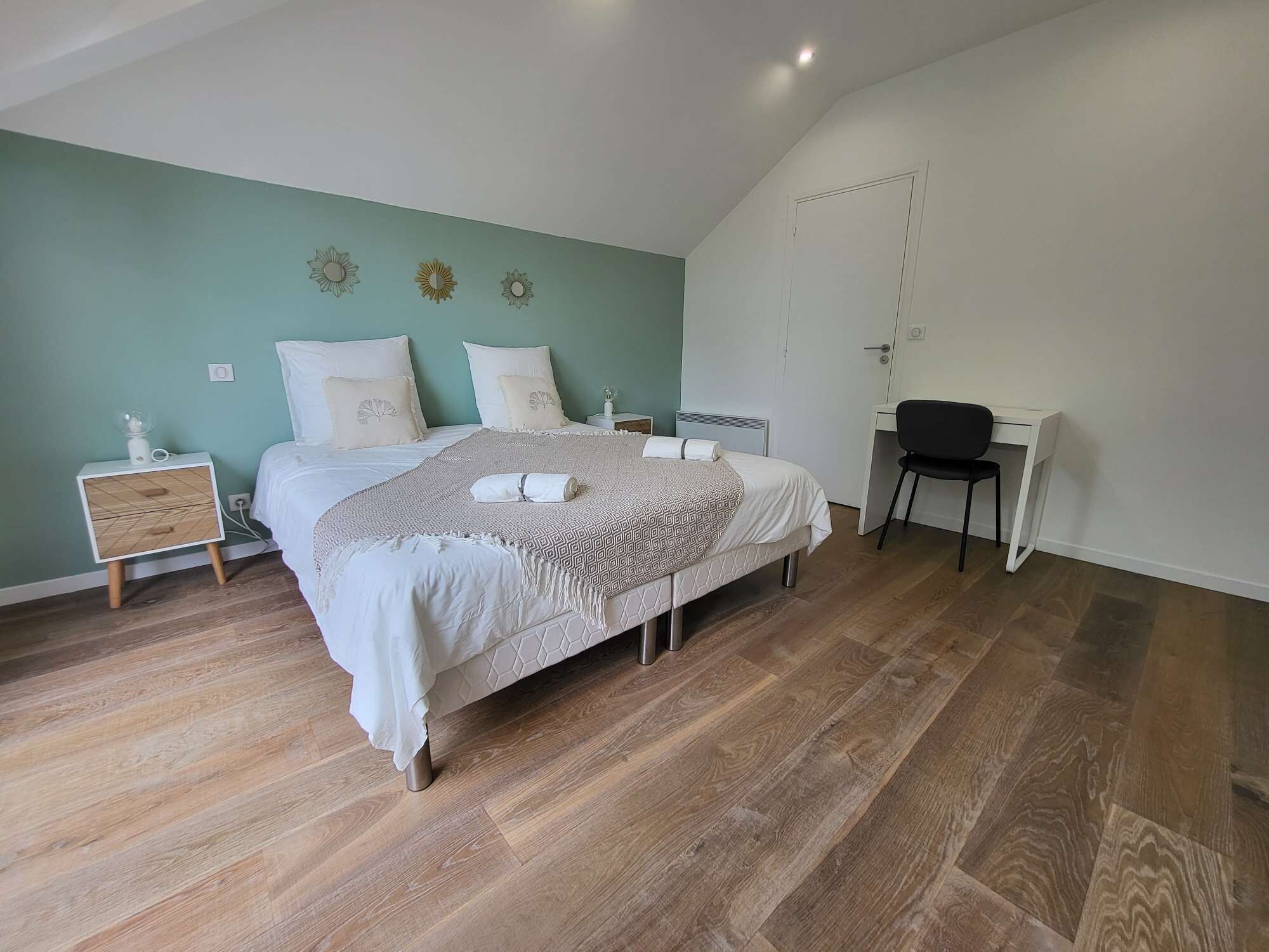 Ein Schlafzimmer mit einem Bett, Nachttischen, einem Schreibtisch und einem Sessel.