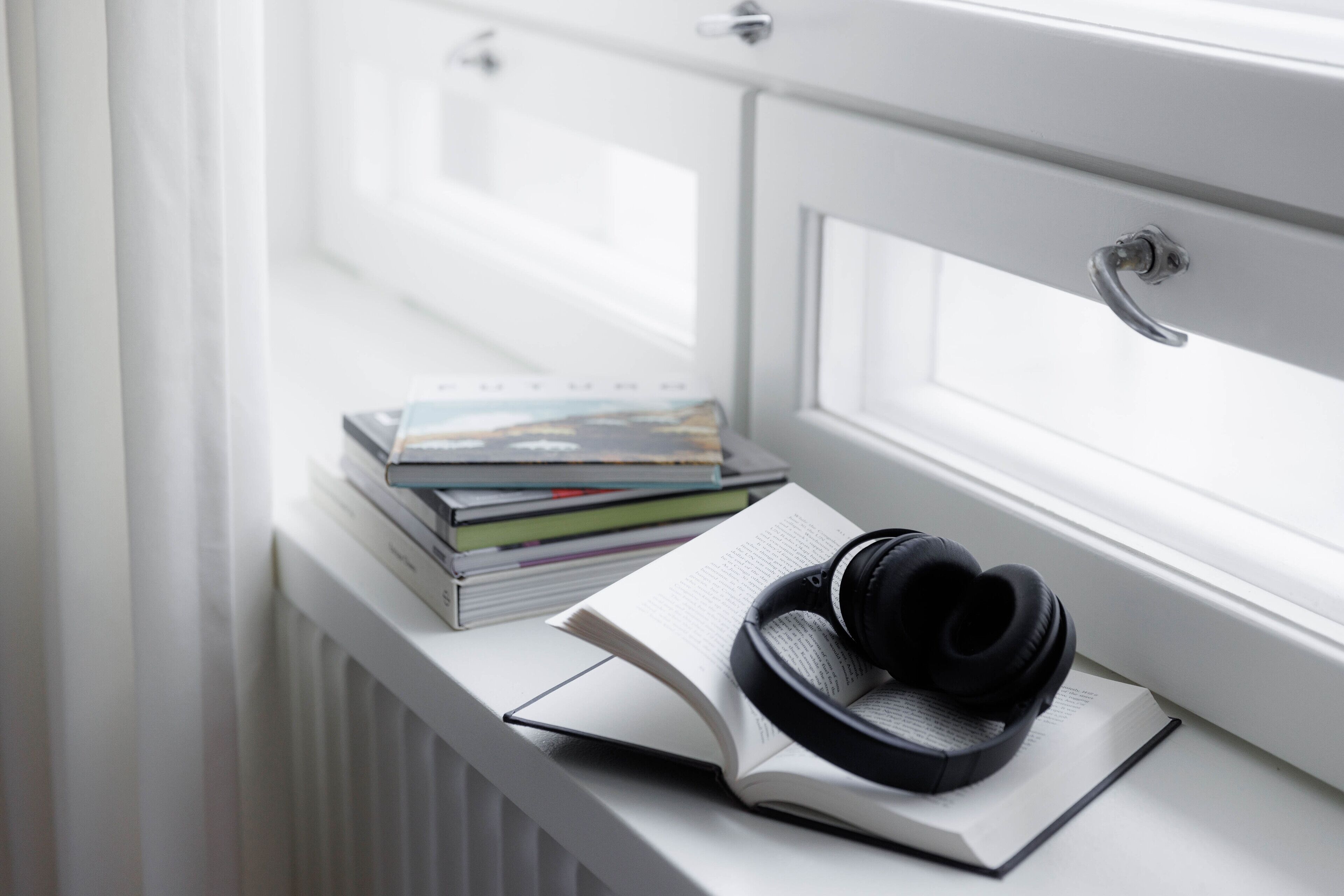 A window sill with a stack of books and a pair of headphones.
