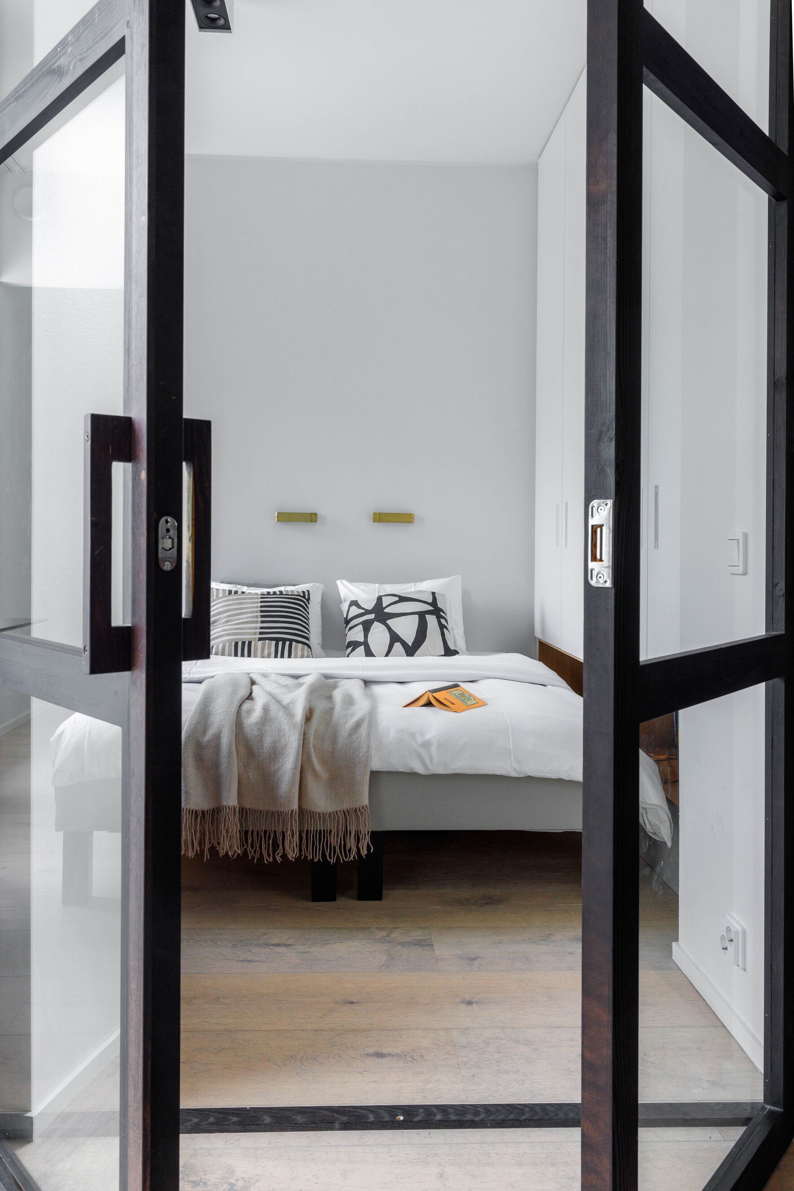 A modern bedroom with a bed, bedside tables, and a wardrobe.