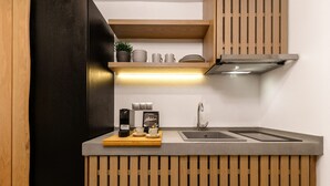 A modern kitchen with a built-in stove, a sink, and wooden paneling. - Soho Exclusive Suites (Thasos)