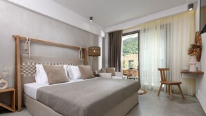 A modern bedroom with a large bed, a wooden headboard, a bedside table, a chair, and a view of the outdoors. - Soho Exclusive Suites (Thasos)