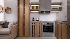 A modern kitchen with a built-in oven, a coffee machine, and wooden paneling. - Soho Exclusive Suites (Thasos)