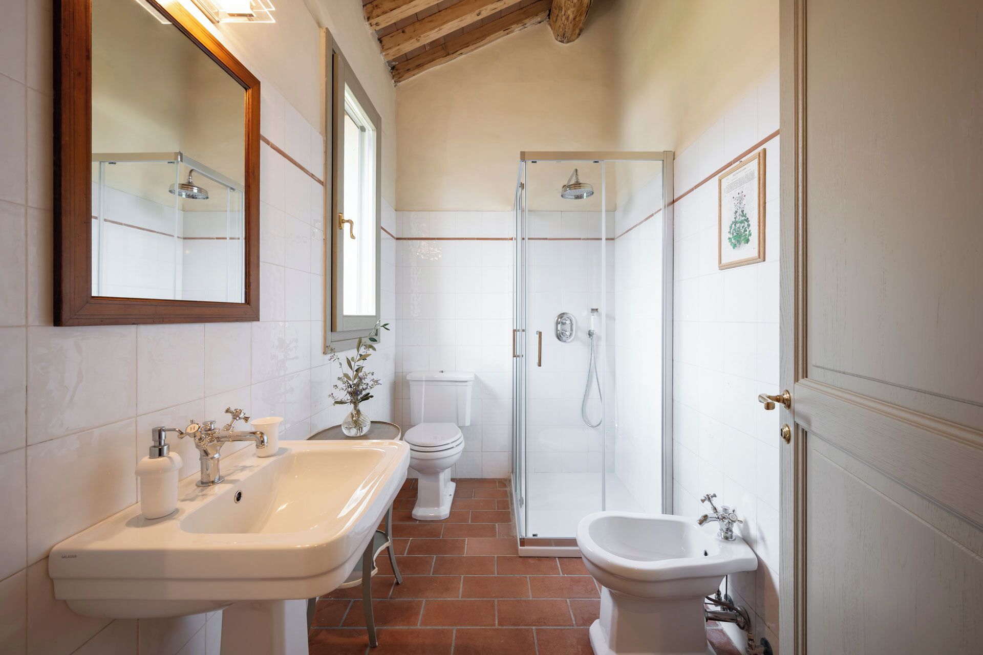 A bathroom with a glass-enclosed shower, a sink, a toilet, and a bidet.