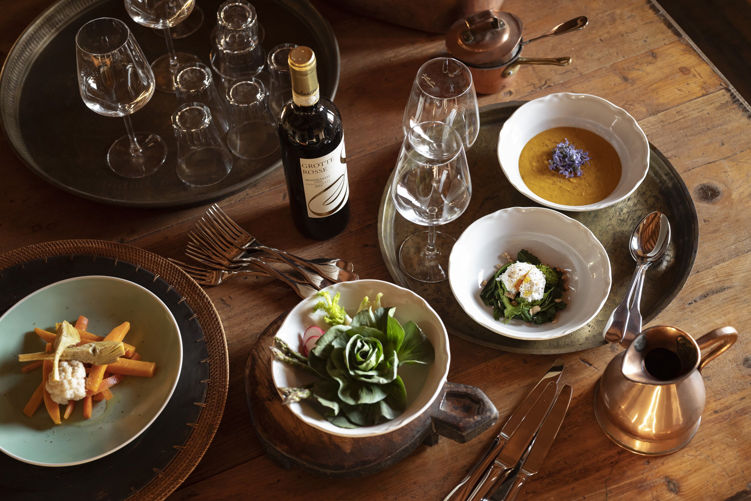 Une table à manger avec différents plats, des verres à vin et des couverts.