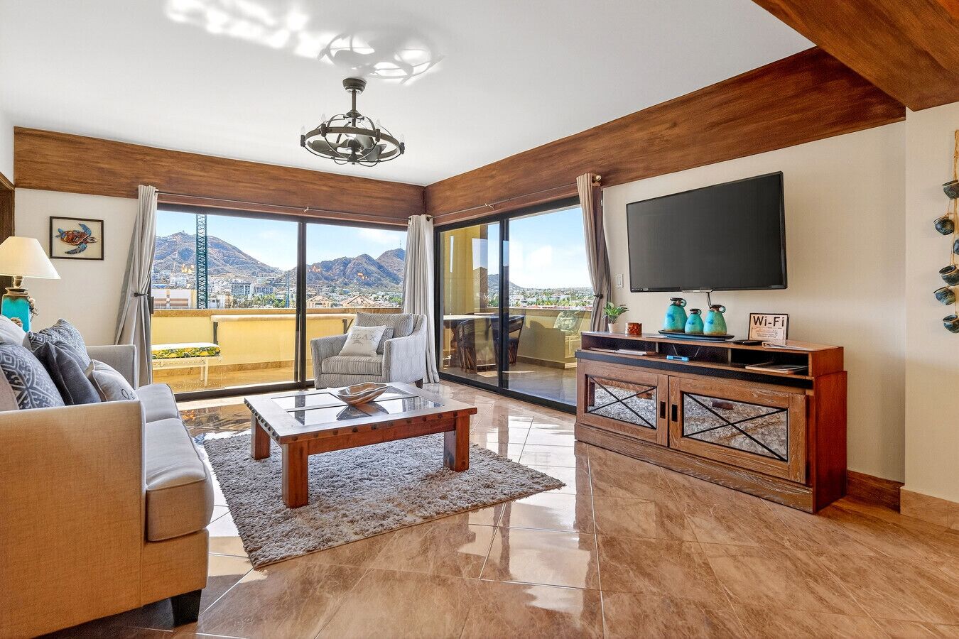 A spacious living room with a sofa, coffee table, and TV, featuring a balcony with a city view.