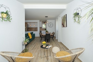 A modern living space with a dining area, kitchen, and a view into another room.