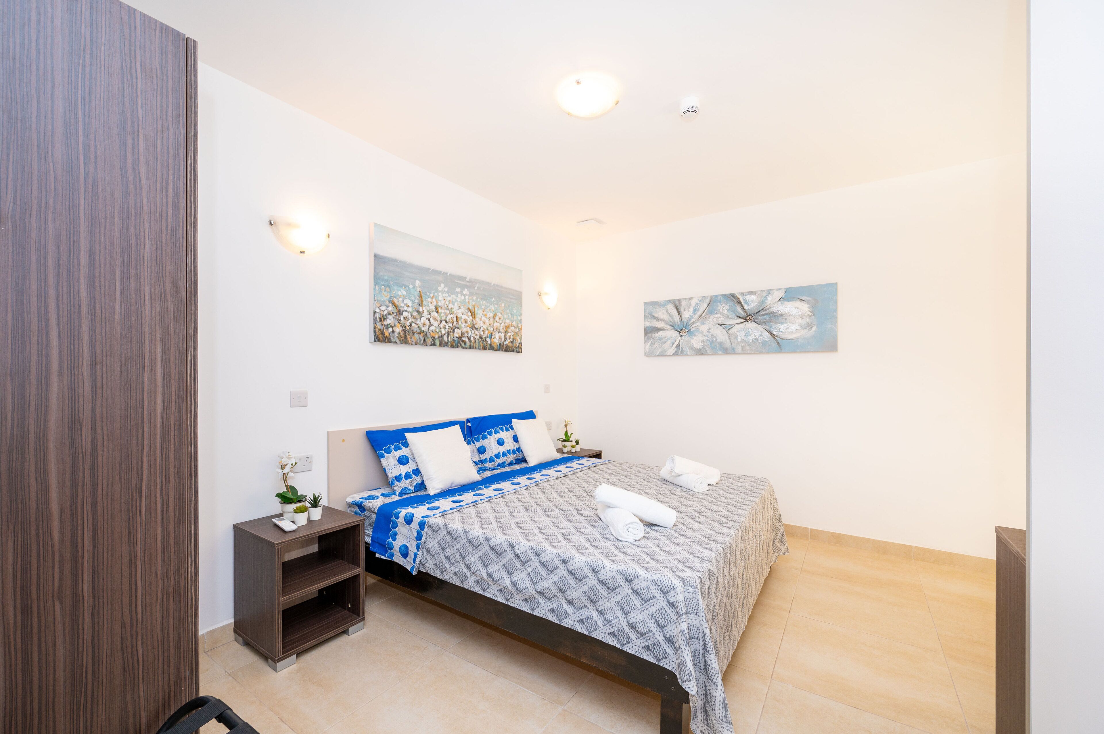 A neatly arranged bedroom with a bed, bedside tables, and wall art.