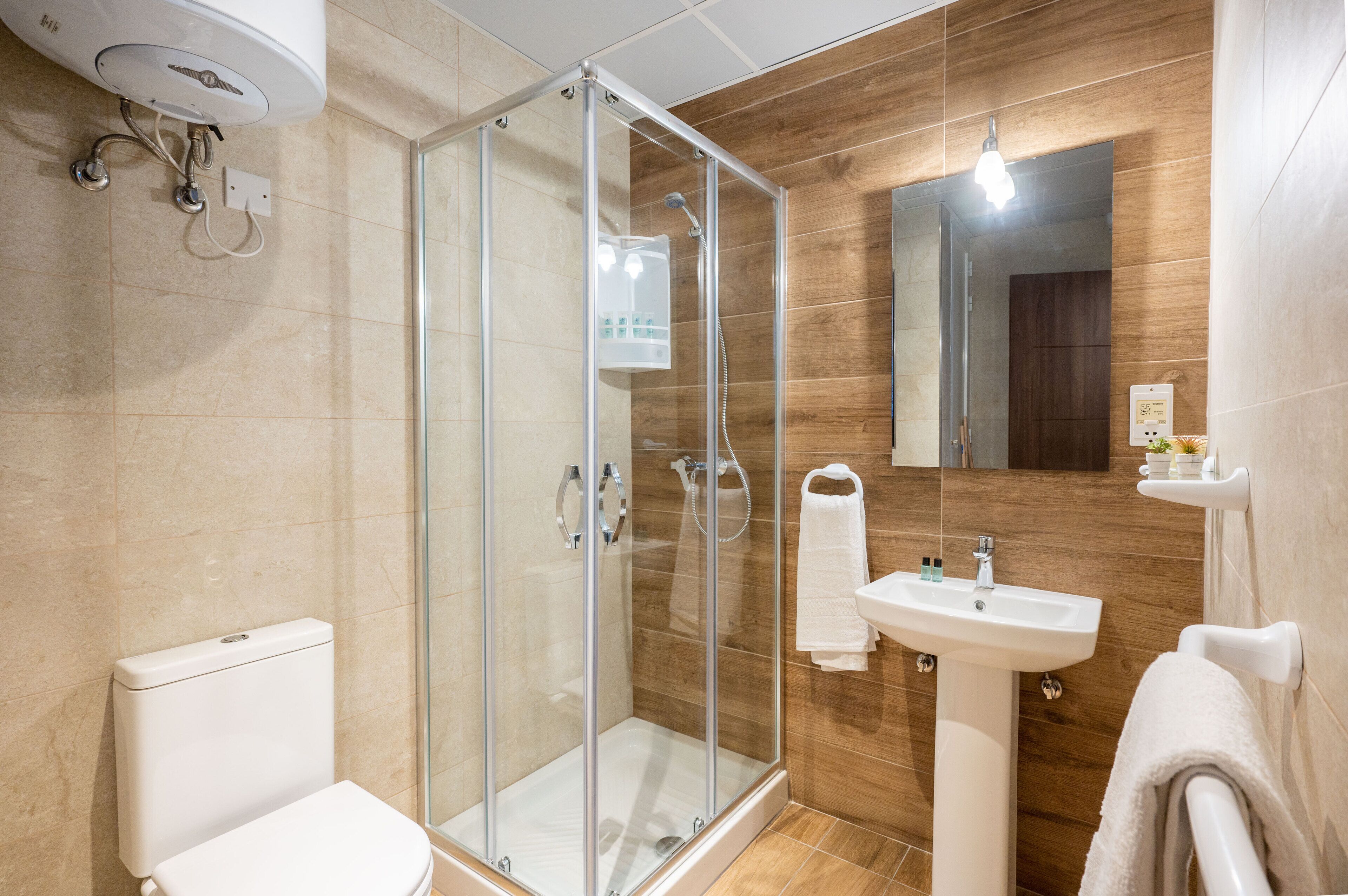 Ein modernes Badezimmer mit einer gläsernen Duschkabine, einem weißen Waschbecken und einer Toilette.