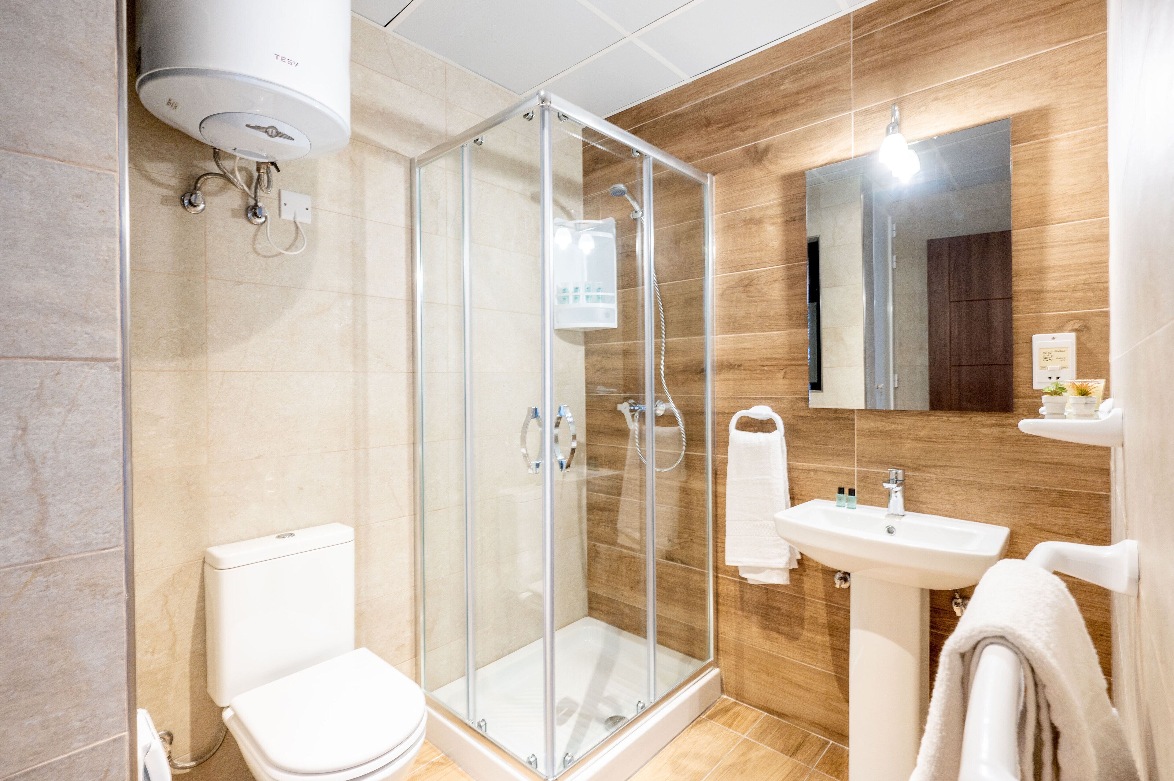 Un baño moderno con ducha de vidrio, inodoro blanco y lavabo con espejo.